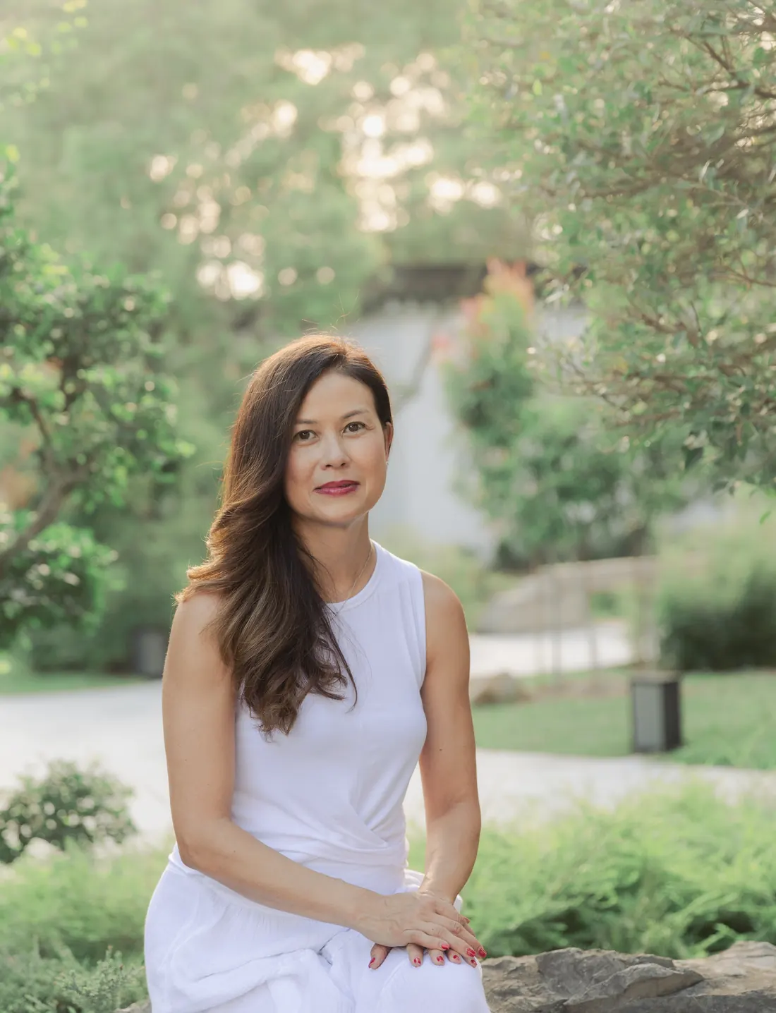 Claire Bostock-Tang seated in a garden, wearing white